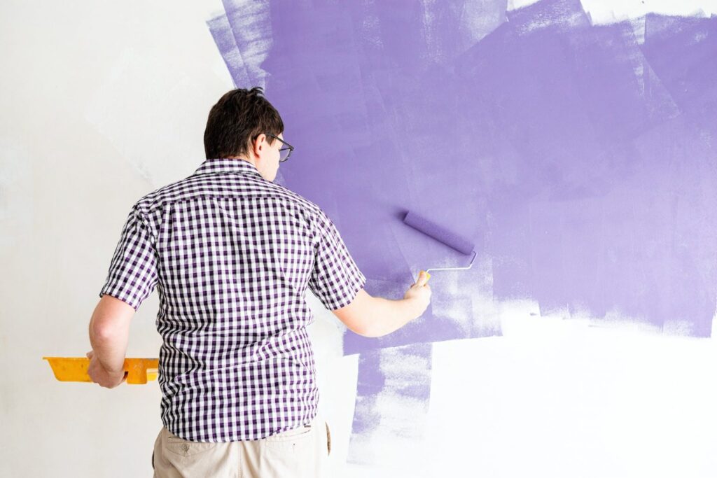 man coloring wall with roller with purple paint 1536x1025